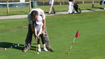 Père initiant sa fille au golf